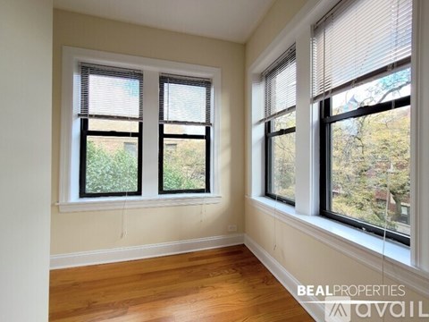 A room with two windows and wooden floors is available for rent.