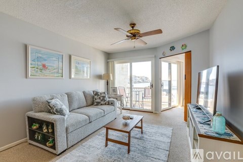 A living room with a grey couch and a ceiling fan.