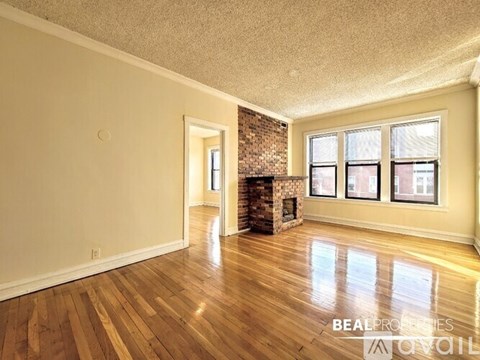 A spacious room with wood flooring and a brick fireplace.