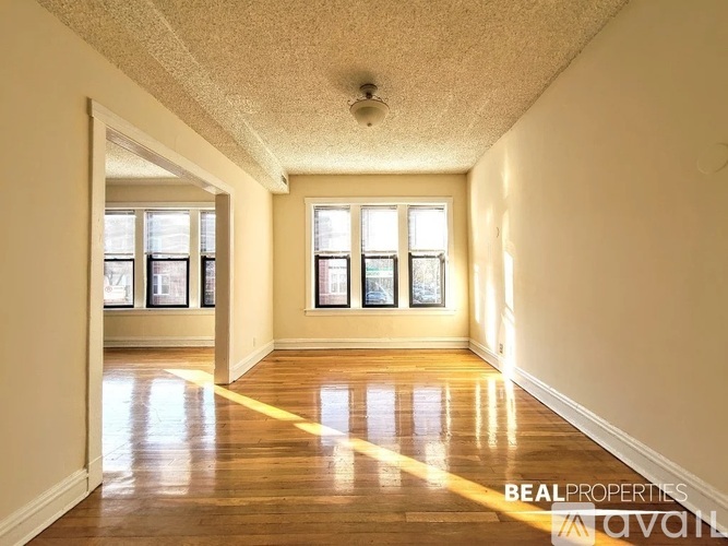 A spacious room with wooden floors and a large window.