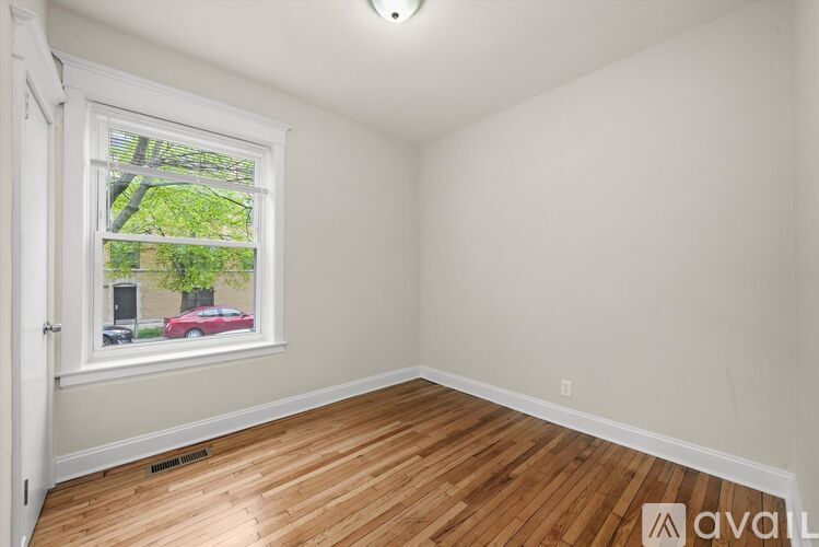 A room with a window showing a red car and trees outside.