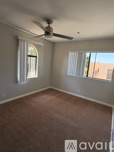A room with a carpeted floor and a ceiling fan.