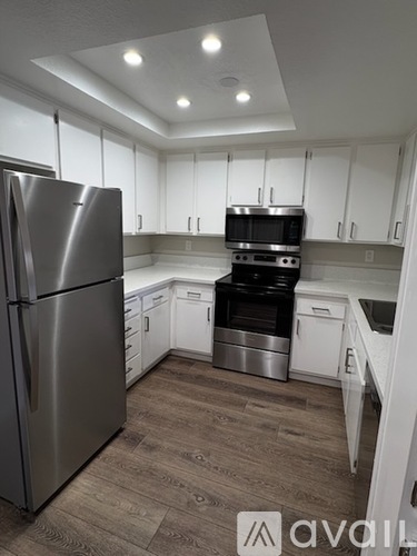 A kitchen with a stainless steel refrigerator and white cabinets.