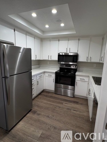 A kitchen with a stainless steel refrigerator and white cabinets.
