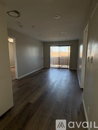 A room with wooden floors and a window with blinds.