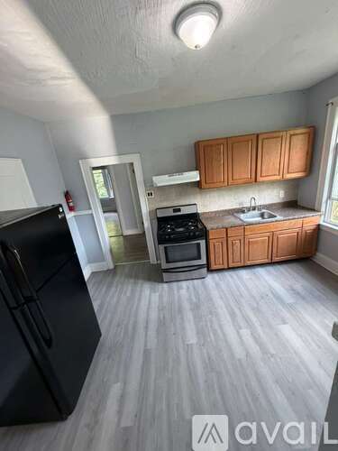A kitchen with a black fridge, stove, and wooden cabinets.