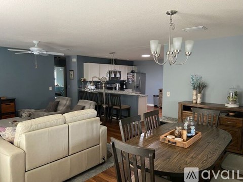 A living room with a white couch and a wooden dining table.