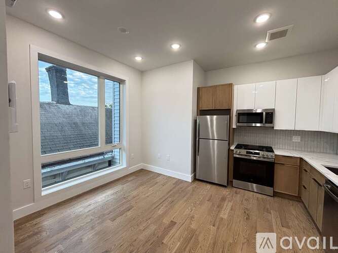 A kitchen with white cabinets and a stainless steel refrigerator.