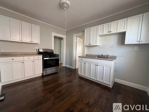 A kitchen with white cabinets and a wooden floor.