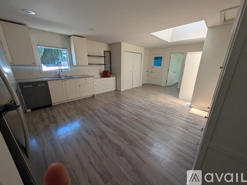 A spacious kitchen with wooden flooring and white walls.