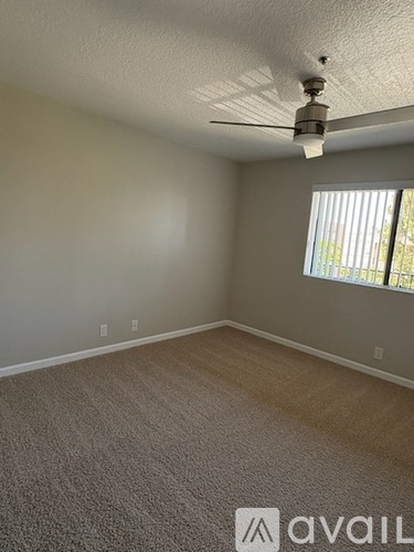 A room with a carpeted floor and a ceiling fan.