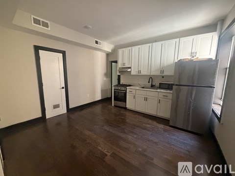 A kitchen with white cabinets and a wooden floor.