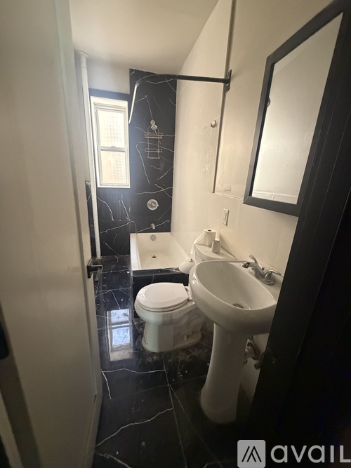 A bathroom with a toilet, sink, and mirror.