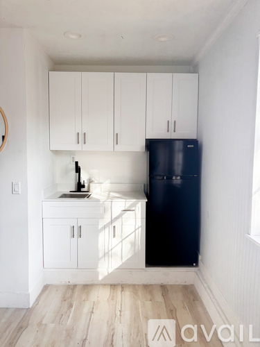A kitchen with white cabinets and a black fridge.