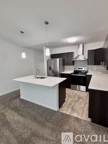 A modern kitchen with a white island and stainless steel appliances.