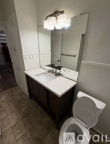 A bathroom with a toilet, sink, and mirror.