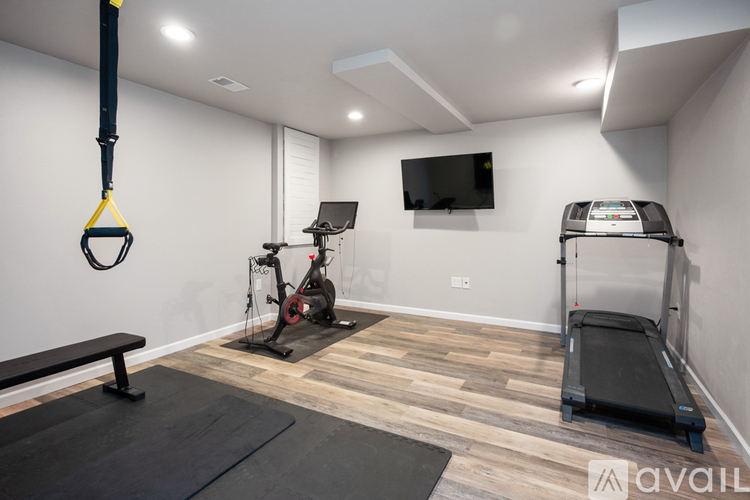 A home gym with a bench, a treadmill, a stationary bike, and a television.