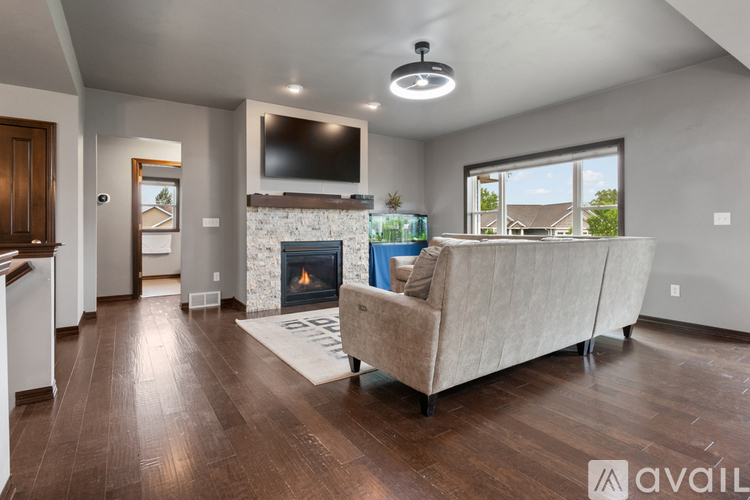 A living room with a stone fireplace and a flat screen TV mounted above it.