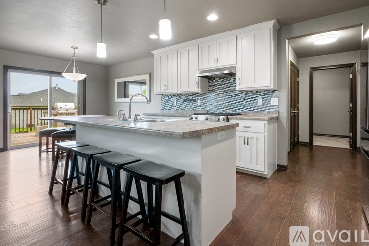 A kitchen with white cabinets and a blue backsplash.