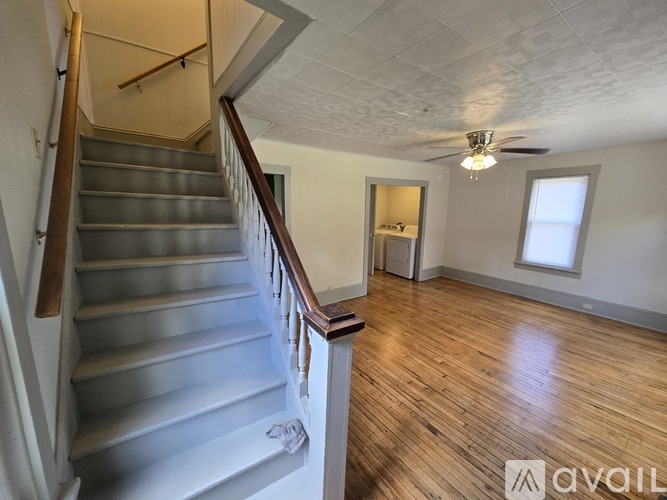 A staircase with a wooden handrail and a light fixture on the ceiling.
