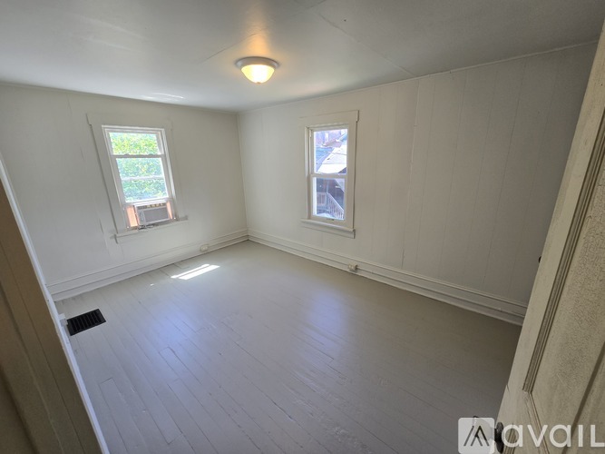 A room with white walls and a window with a view of trees.