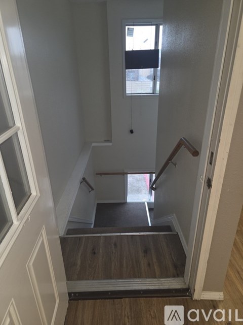 A stairway with a wooden handrail and steps leading to a doorway.