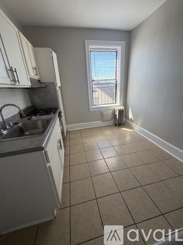 A kitchen with white cabinets and a window overlooking a balcony.