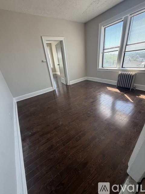 A room with wooden flooring and a window with blinds.