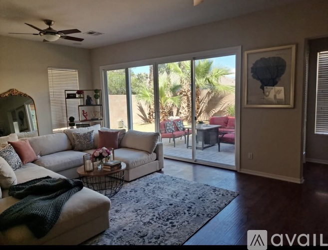 A living room with a couch, a table, and a fan.