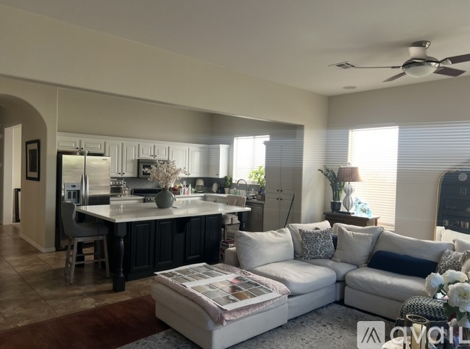 A modern living room with a kitchen area in the background.