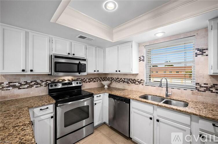 A kitchen with granite countertops and white cabinets.