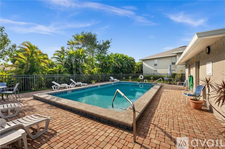 A pool surrounded by chairs and trees.