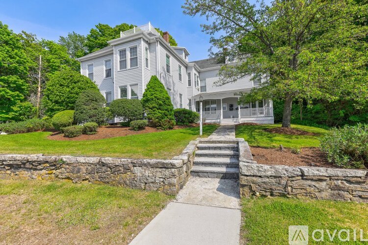 A large house with a stone wall and a pathway leading to the front door.