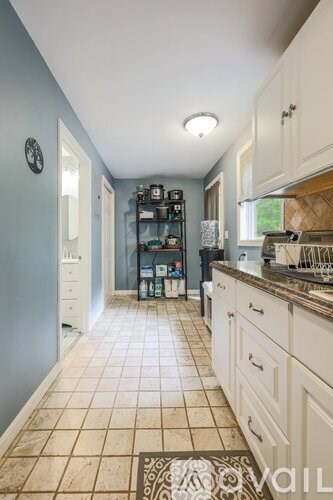 A kitchen with white cabinets and a tiled floor.