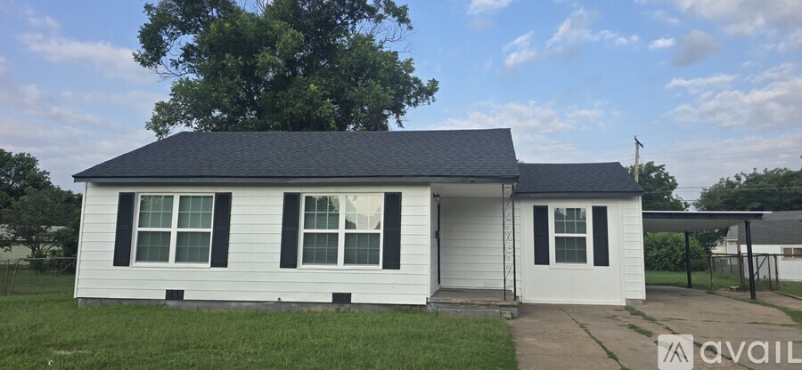 A small white house with a black roof and a sign that says "available" in front of it.