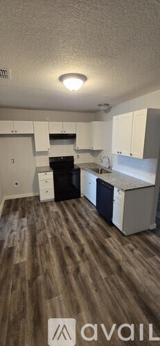 A kitchen with white cabinets and a wooden floor.