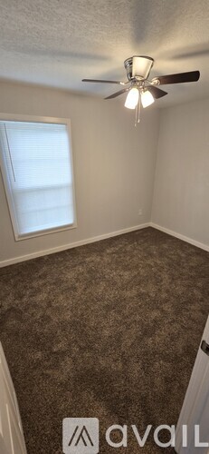 A room with a ceiling fan and carpeted floor.