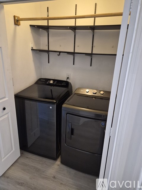 A small kitchen with two black ovens and a white door.