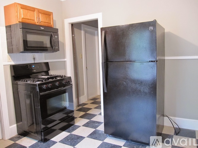 A black and white checkered floor in a kitchen with a black oven, black microwave, and black refrigerator.