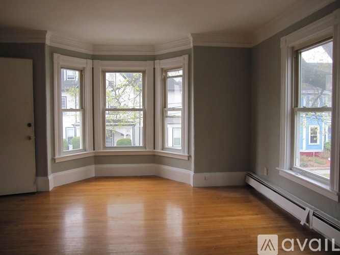 A room with wooden floors and three windows.