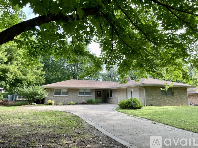 A house with a driveway and trees in front of it.