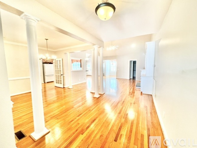 A spacious room with wooden floors and white walls.