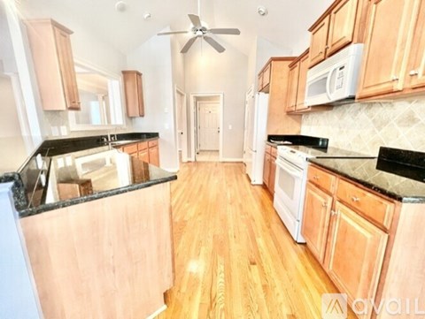 A kitchen with wooden cabinets and black countertops.