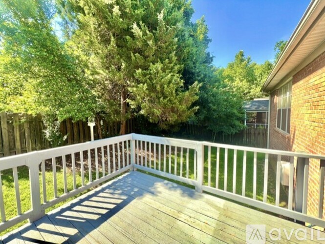 A deck with white railings and a white railing is surrounded by trees.