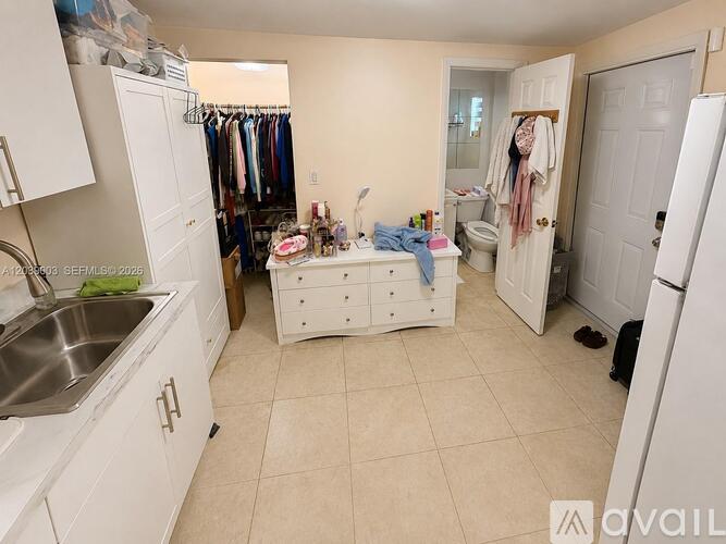 A small, clean, and organized bedroom with a white dresser and a white refrigerator.