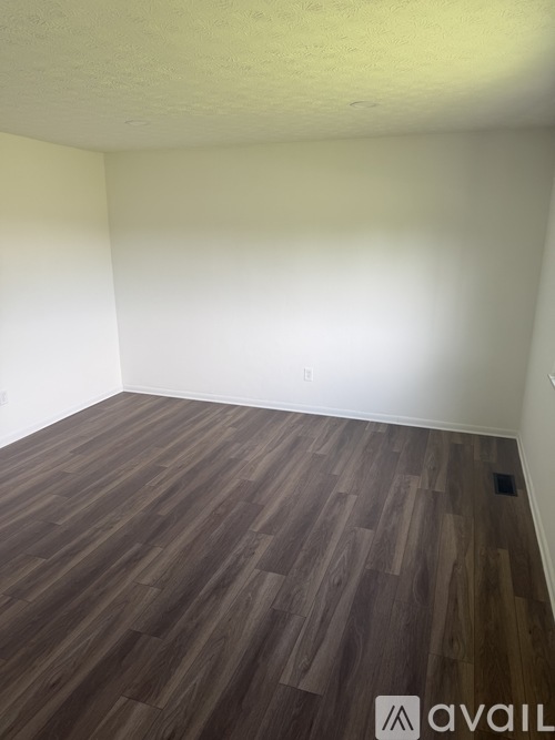 A room with wooden flooring and a white wall.
