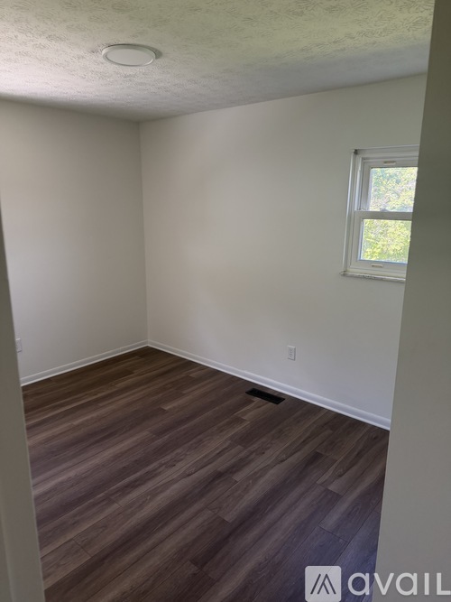 A room with wooden flooring and a window.