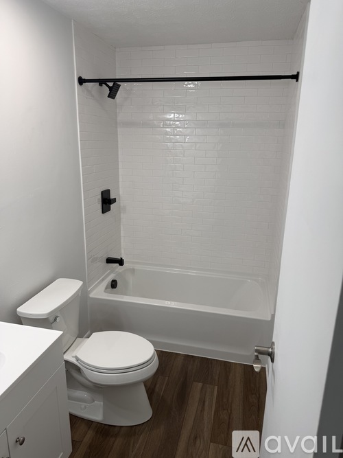 A white toilet sits next to a white bathtub in a small bathroom.