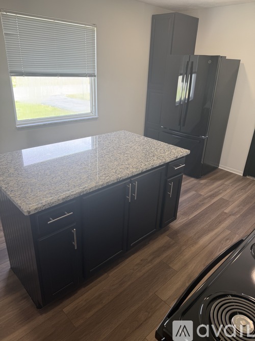 A kitchen with a granite countertop and dark wood cabinets.