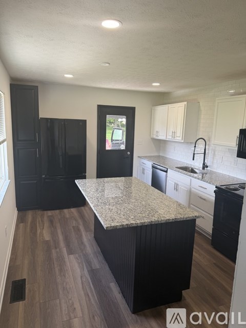 A kitchen with black cabinets and a granite countertop.